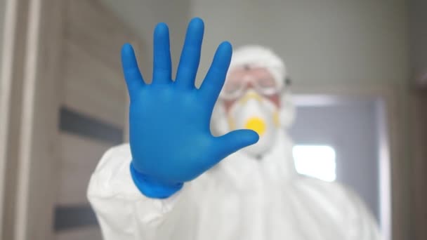 Koronavirová epidemie, nebezpečný virus, boj proti šíření infekce. Muž v ochranném obleku s rukavicemi a dýchacím přístrojem ukazuje, že se zastavil. — Stock video