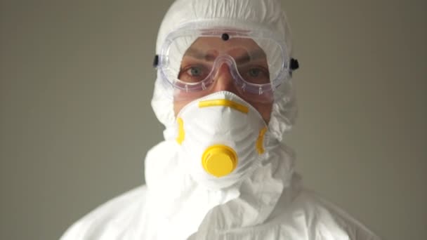 Close portrait of a man in a protective suit and blue gloves shows a thumbs up gesture, bad news, the spread of coronavirus, an aggressive gesture — Stockvideo