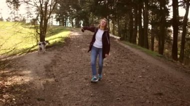 Ön manzara, kız arkasını dönüyor. Genç bir kadın köpeğiyle parkta bir yol boyunca yürüyor. Karatentin sırasında bir köpekle yürüyüşe çıkmak. Mutlu aile hafta sonu