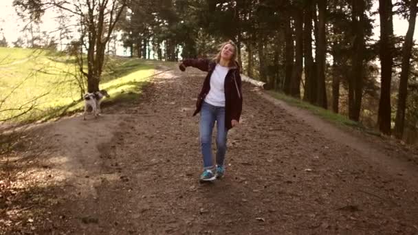 Pohled zepředu, dívka se otočí. Mladá žena kráčí po cestě v parku se svým psem. Procházka se psem během karatentinu. Šťastný rodinný víkend — Stock video