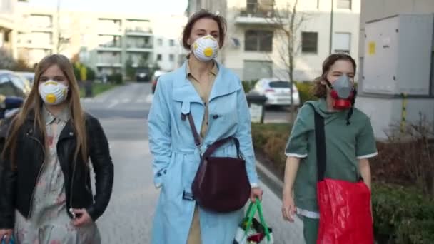 Ung kvinna och två barn till tonåringar är maskerade längs gatan. Matinköp under koronoviruspandemin. Coronavirus Covid19 — Stockvideo
