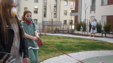 Maskeli çocuklar şehirde köpeklerini tasmayla gezdiriyorlar. Coronovirüs salgını, Covid-19
