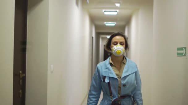 Beautiful woman in a blue cloak and a protective mask from the coronovirus Covid-19 enters the entrance of her house and opens the door with a key. Quarantine during an epidemic, self-isolation — Stock Video