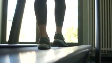 Kapalı portre. Koşu bandında spor ayakkabılı kadın bacakları. Spor salonu ya da apartmanın içinde. Sağlıklı yaşam tarzı