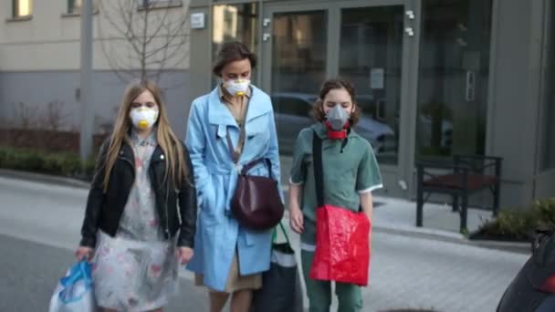 Coronovirus pandemi. En familj på tre, en maskerad man och två barn, en pojke och en flicka, går hem på en stadsgata. Nödordning, karantän i Europa — Stockvideo