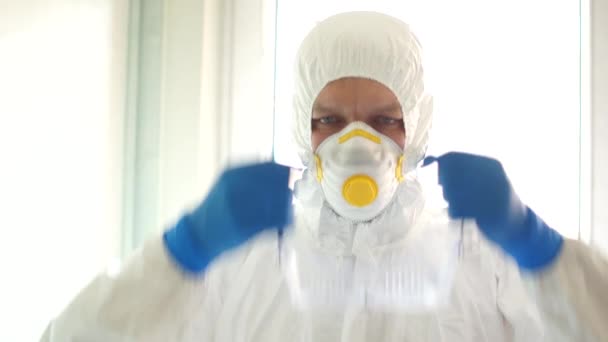 Close portrait of a man in a protective suit wears plastic safety glasses. Medical workers, the threat of the spread of coronavirus, medical remedies, covid-19 — Stock Video