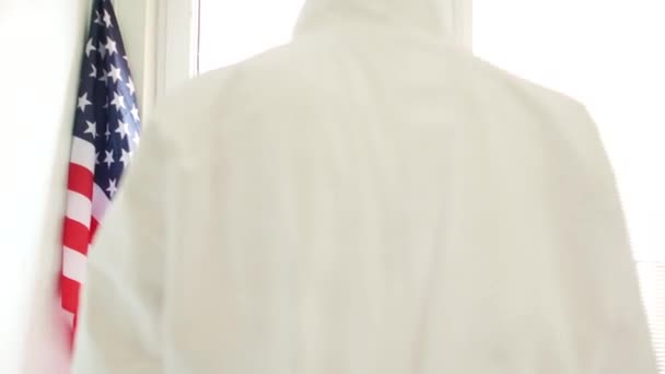 Vittime del coronovirus negli Stati Uniti. La silhouette sfocata di un medico in una tuta protettiva va in lontananza attraverso una porta di vetro. Epidemia di Covid-19 negli Stati Uniti d'America — Video Stock