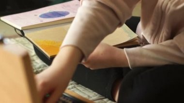 Kız eskiz defterine felsefi resimler çiziyor. Karantina ve kendini izole etme süresince çocukların yaratıcılığı, renkli kalem çizimleri