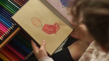 Yakın plan, bir kız pastel boyayla resim çiziyor. Yüzü yerine soru işareti olan figür adam, felsefi sorular. Karantina ve kendini izole etme süresince çocuk yaratıcılığı