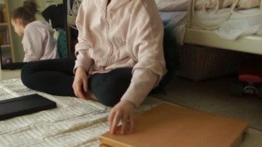 Odasındaki kız resim yapmaya hazırlanıyor. Renkli kalemlerle dolu büyük bir kutu açıyor ve çizimleriyle defterini açıyor. Karantina sanatı