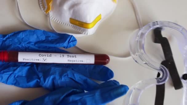 Szczepionka przeciw koronowirusowi. Stół jest probówką z próbką osocza krwi z dodatnim wynikiem testu na obecność koronowirusa covid-19 i szczepionką znakowaną ampułką. Ochronna maska medyczna i okulary, rękawiczki — Wideo stockowe