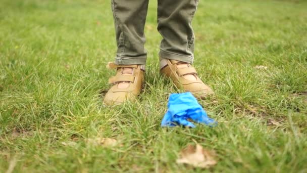 Coronovirus epidemie en ecologie. Medisch afval. Close-up van mannelijke benen, een man gooit medische handschoenen en een beschermend masker op het gras — Stockvideo