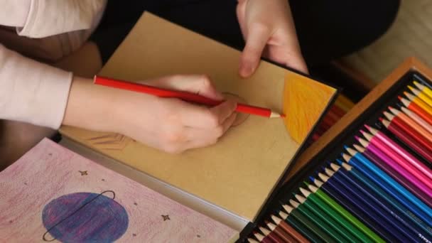 Las manos de los niños dibujan con lápices a color dibujos en una caja de bocetos. Planeta y figura humana con signo de interrogación. El futuro del planeta — Vídeo de stock