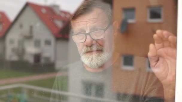 家の窓の近くに悲しい老人。コロナウイルス隔離概念。年齢別リスク群 — ストック動画