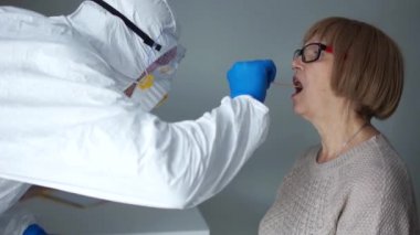 Coronovirus aile risk grubunu test ediyor. Koruyucu kıyafetli doktor önce yaşlı bir kadın emekliden, sonra da kocasından örnek alıyor. PCR reaksiyonundan zararsız tanı yöntemi