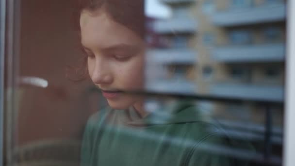 Děti během karantény. Kudrnatý školák smutný u okna, sklonil hlavu na sklo, během izolace sklíčený. Karanténa Coronovirus Covid-19 — Stock video