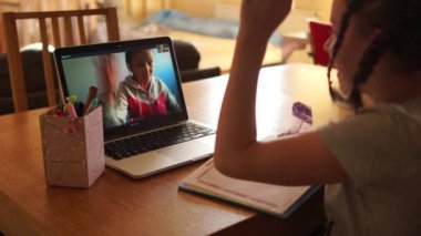 At kuyruklu kız öğrenci Skype 'ta öğretmeniyle konuşuyor, el sallıyor. Coronovirus Covid-19 sırasındaki karantina. Karantina ve Sosyal Mesafe kavramı, uzaklık öğrenimi