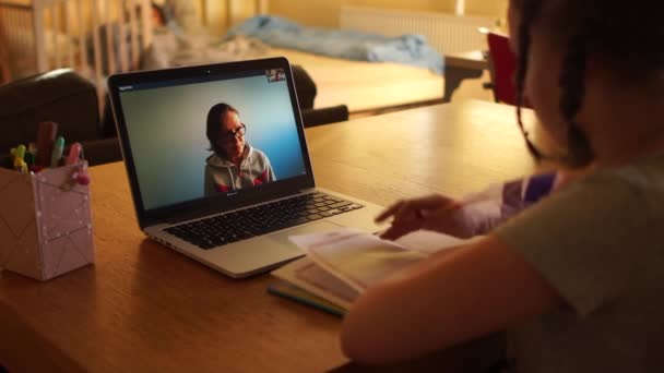 Skype 'ta öğretmeniyle konuşan bir kız. Coronovirus Covid-19 sırasındaki karantina. Karantina ve sosyal uzaklık kavramı, uzaktan öğrenme. Evden öğrenirken dizüstü bilgisayar kullanan küçük kız. — Stok video