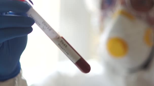 Coronovirus uitbraak. Artsen handen houden een reageerbuis met een bloedmonster voor onderzoek nieuwe snel verspreidende Coronavirus Covid-19. Positieve test — Stockvideo