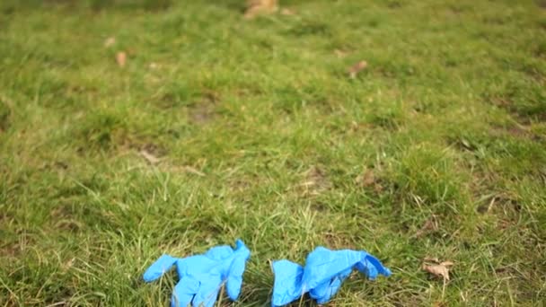 Milieuvervuiling met medisch plastic. Quarantaine en ecologie. Clouse up portret van voeten onherkenbare jongen geschikt voor handschoenen op het gras en schoppen ze. Coronovirus covid-19 — Stockvideo