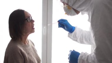 Koronovirüs PCR teşhisi. Laboratuvar asistanı mikrobiyolog yaşlı bir hastanın ağız boşluğundan DNA örneği alıyor. Coronovirüs testi covid-19