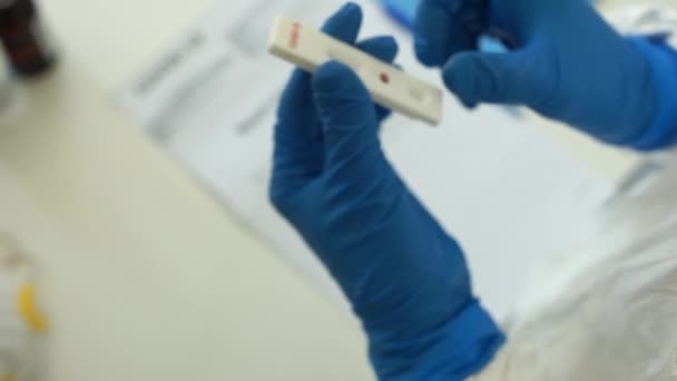 Arzt mit einem Testkit für die Viruserkrankung COVID-19 2019-nCoV. Das Laborkartenkit testete NEGATIVE auf Viren des neuartigen Coronavirus SARS-CoV-2. Schnelltest covid 19 — Stockvideo