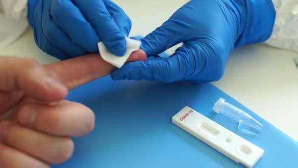 Tomar un análisis de sangre para el coronovirus covid-19 en un laboratorio. Procesando un dedo con una toallita desinfectante. Test rápido covid 19 — Vídeos de Stock