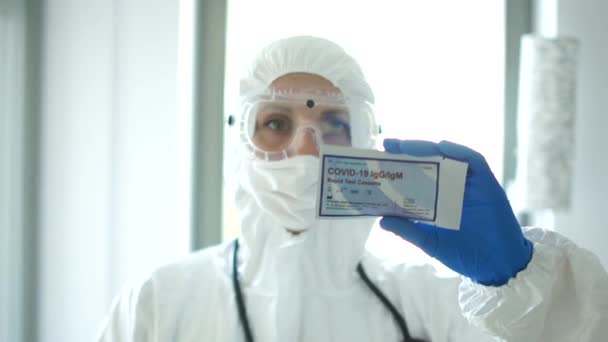 Wroclaw Poland - April 23, 2020. Rapid test covid 19. Close portrait of a doctor woman in a protective suit whis test cassette for detecting the covid-19 virus by the invasive PCR diagnostic method — Stock Video