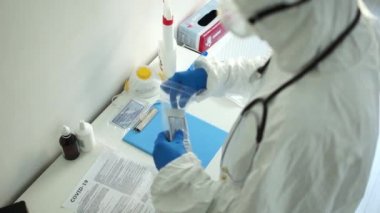 Wroclaw Polonya - 23 Nisan 2020. Hızlı test covid 19. Koruyucu giysili doktor ve eldivenli doktor covid-19 tanı kitini açar. Test kaseti, alkol bezi, korkuluk, pipo, test tüpü ayıracı.