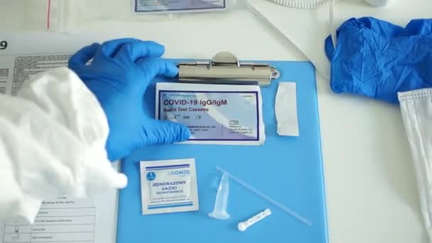 Wroclaw Polen - 23 april 2020. Snelle test covid 19. Dokter in een beschermende handschoenen opent de covid-19 diagnostiekkit - testcassette, alcoholdoekje, scarifier, pipet, reageerbuisreagens — Stockvideo