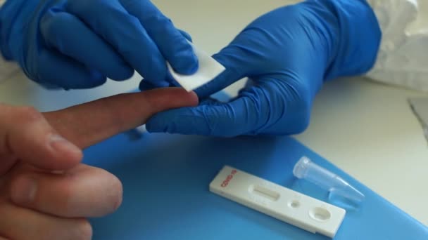Die Bearbeitung eines Fingers mit einem Desinfektionsmittel. Schnelltest covid 19. Ein Bluttest auf Coronovirus covid-19 in einem Labor. Testkassette zum Nachweis von SARS-CoV-2 Viren — Stockvideo