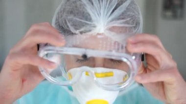 Koronavirüs salgını sırasında kadın doktor gözlük ve koruyucu maske takar. Maskeden ve kırmızı noktalardan yüz izleri görünür. Yorgun bir doktorun yakın portresi