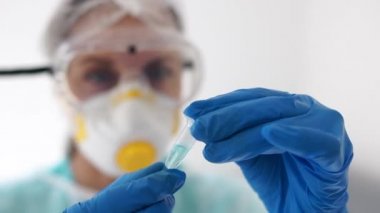 Coronovirus covid-19 SARS-CoV-2 için aşı ve tedavi arayın. Elinde mavi bir sıvıyla test tüpü tutan bir kadın doktorun yakın portresi. Laboratuvar araştırması