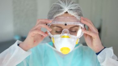 Yorgun bir doktorun yakın portresi. Koronavirüs salgını sırasında kadın doktor gözlük ve koruyucu maske takar. Maskeden ve kırmızı noktalardan yüz izleri görünür.