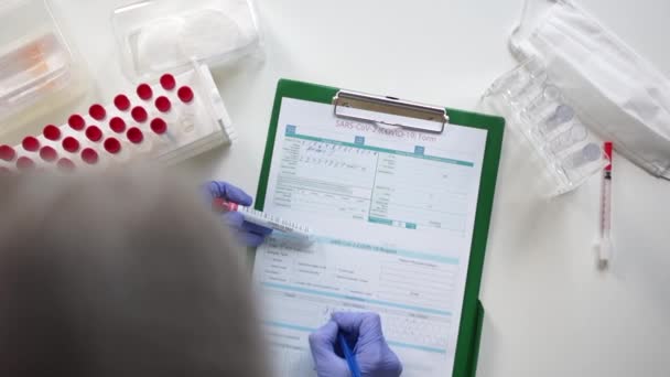 Ο γιατρός στο εργαστήριο κρατάει δοκιμαστικό σωλήνα για ιογενή νόσο COVID-19 2019-nCoV. Εργαστηριακή καταγραφή των αποτελεσμάτων των δοκιμών για ιογενή μυθιστόρημα coronavirus sars-cov-2 — Αρχείο Βίντεο