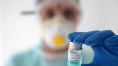 Bağışıklık, tedavi Covid-19 Coronavirus. Koruyucu maskeli ve gözlüklü bir kadın doktorun yakın portresi elinde bir test tüpü, elinde de kovan aşısı olan 19 sars-cov-2.