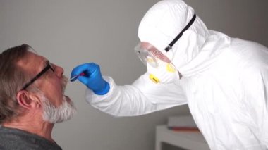Hızlı test covid 19. PCR reaksiyonu kullanarak SARS-CoV-2 'ye antikorları tespit etmek için zararsız bir yöntem. Koruyucu kıyafetli yaşlı adam ve doktor.