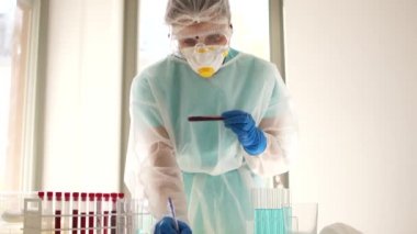 Laboratuvar asistanı üzerinde enfekte olmuş Covid-19 kan örneği olan bir test tüpü aldı. Laboratuvar çalışanı Coronovirus covid-19 sars-cov-2 testlerinin sonuçlarını kaydediyor.