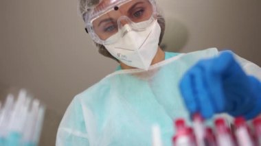 Sars-CoV-2 teşhisi. Laboratuvardaki güzel kız laboratuvar asistanı üzerinde Coronovirus Covid-19 enfeksiyonlu kan örneği olan bir test tüpü tutuyor.