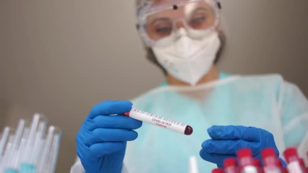 Positieve coronovirus test. Microbioloog in het laboratorium houdt een reageerbuis met een bloedmonster geïnfecteerd met coronovirus covid-19 sars-cov-2. De inscriptie op de reageerbuis covid-19 positief — Stockvideo