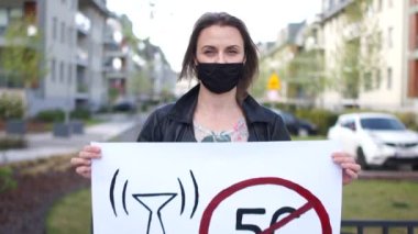 Mobil Kuleler 5G 'nin kurulmasına karşı tek bir protesto. Siyah koruyucu maskeli, posterli bir kızın yakın portresi.