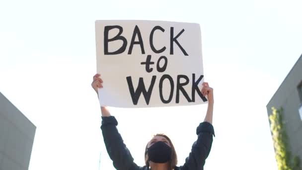 Porträt einer jungen Frau mit einem Plakat mit der Aufschrift Back to work auf einem Hintergrund des Frühlingshimmels. Sozialproteste während der Blockade — Stockvideo