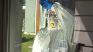 Salgın koronovirüs kovid 19, tıbbi çöküntü. Koruyucu kıyafetli çok yorgun bir doktor maskeyi çıkarır ve eliyle cam pencereye yaslanır. Doktorlar sıkı çalışma konsepti