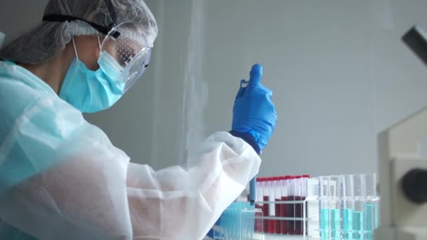 Laboratorní asistent drží pipetový dávkovač pro práci s činidly. Studie krevních vzorků infikovaných virem covid-19. Hledání vakcíny, sérologická analýza krve — Stock video