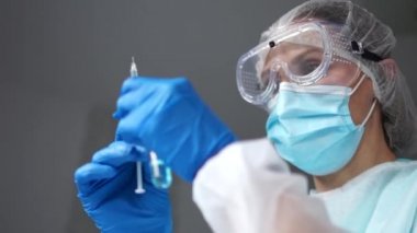 Tıbbi maskeli doktor elinde ampul ve Coronavirus aşısı olan şırınga tutuyor. Coronavirus COVID-19 'a karşı bir ilaç. Ampullerdeki antiviral aşıyı uygulamaya hazırlayın.