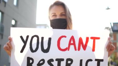Siyah maskeli ve posterli bir kızın güneşli portresi. Haklarımızı kısıtlayamazsın. Karantina covid-19 sırasındaki kısıtlayıcı tedbirlere karşı sosyal protesto