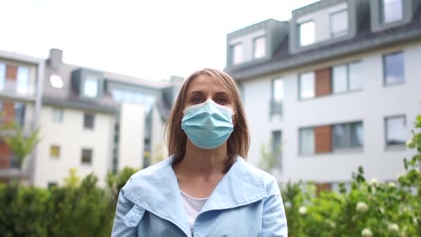 Городской портрет девушки в маске. Красивая женщина в синем пальто и медицинской маске. Концепция аллергии, пандемический коронавирус covid-19 — стоковое видео