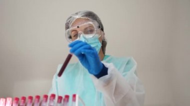 Laboratuvarda, analiz ve Covid-19 enfeksiyonlu diyabet örneği için biyolojik bir tüp olan bir doktor var. Laboratuvar teknisyeni kimyasal kan testi yapıyor. Sonuçları kaydet