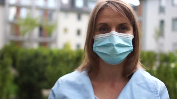 Счастливая позитивная девушка, молодая красивая женщина снимает защитную стерильную медицинскую маску с лица на открытом воздухе, улыбаясь. Счастливый конец. Победа над коронавирусом. Пандемический Ковид-19 — стоковое видео