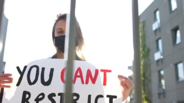 Haklarımızı kısıtlayamazsınız. Maskeli ve posterli bir kızın yakın portresi. Kilitleme sırasında Avrupa 'da sosyal protestolar, zorunlu aşılamaya karşı protestolar